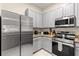 Updated kitchen showcasing stainless steel appliances, light gray cabinetry, and tile flooring at 110 Watling Way # 25204, Davenport, FL 33837
