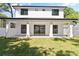 A home backyard shows a covered patio, large green space, white exterior with black trim, and a double door sliding glass entry at 1217 Cloverlawn Ave, Orlando, FL 32806
