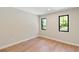 A home bedroom shows light hardwood floors, neutral colored walls, and windows with black trim at 1217 Cloverlawn Ave, Orlando, FL 32806