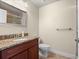 Bathroom featuring a granite vanity, mirror, toilet, and walk-in shower at 1319 Johns Cove Ln, Oakland, FL 34787