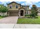 Stunning two-story home with lush landscaping, a well-manicured lawn, and a brick driveway at 1403 Rolling Fairway Dr, Davenport, FL 33896