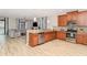Open kitchen with wood cabinets, stainless steel appliances, and an island with views of the living room at 1403 Rolling Fairway Dr, Davenport, FL 33896