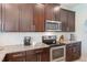 Close up of modern kitchen with stainless steel oven, granite counters and dark wood cabinetry at 15241 Sunrise Grove Ct, Winter Garden, FL 34787