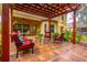 A covered patio with red pergola featuring tiled flooring, tropical landscaping, and red outdoor furniture at 1933 Darlin Cir, Orlando, FL 32820