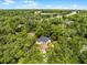 An aerial view of a quaint house surrounded by a lush green forest on a sunny day at 2 Rollingwood Trl, Deland, FL 32724