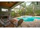 A view of the screened pool area with chairs, a ceiling fan, and a built-in hot tub and lush landscaping at 3372 Bellington Dr, Orlando, FL 32835