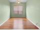 Empty bedroom with light green walls, window with blinds, ceiling fan, and wood floors at 3593 Scoutoak Loop, Oviedo, FL 32765