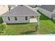 Aerial view of the backyard featuring a covered patio, lush green lawn, and white vinyl fence at 417 Tisone Ln, Davenport, FL 33837
