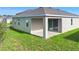 Rear exterior view of home showing the covered patio, siding, and manicured lawn at 417 Tisone Ln, Davenport, FL 33837