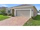 Attractive home showcasing a two-car garage, brick driveway, and lush green lawn at 417 Tisone Ln, Davenport, FL 33837
