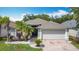 Charming single-story home with a brick driveway, a well-kept lawn, and lovely tropical landscaping at 4611 Cumbrian Lakes Dr, Kissimmee, FL 34746
