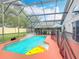 Screened in pool area with waterfall feature, safety fence, and blue patio umbrella at 4611 Cumbrian Lakes Dr, Kissimmee, FL 34746