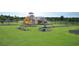 Vibrant community playground with varied play structures and safety surfacing, surrounded by lush green grass at 4850 Waltham Forest Dr, Davenport, FL 33837
