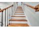 Elegant wooden staircase featuring wooden steps, white risers, and wrought iron railings at 491 Whistling Duck Trl, St Cloud, FL 34771