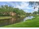 Scenic view of the building by the pond, surrounded by trees and green grass at 500 Mirasol Cir # 203, Celebration, FL 34747