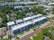 An aerial view of new townhomes with modern design, white roofs, and brick streets surrounded by lush trees at 56 W Harding St, Orlando, FL 32806