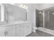 Modern bathroom featuring dual sinks, white cabinetry, a glass-enclosed shower, and neutral tile flooring at 56 W Harding St, Orlando, FL 32806