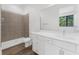 Modern bathroom with a walk-in shower, white vanity, large mirror, and sleek fixtures in a neutral color palette at 56 W Harding St, Orlando, FL 32806