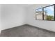 Minimalist bedroom with grey carpet, white walls, and a large window providing natural light and a view of the outside at 56 W Harding St, Orlando, FL 32806