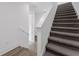 Carpeted staircase with white railing and gray wood flooring creates a clean, modern aesthetic in the foyer at 56 W Harding St, Orlando, FL 32806