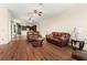 Open-concept living area with hardwood floors, leather sofas, and a view of the kitchen, perfect for entertaining at 6234 Tremayne Dr, Mount Dora, FL 32757