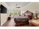 A spacious primary bedroom with a tray ceiling, wood floors, and large windows at 6234 Tremayne Dr, Mount Dora, FL 32757