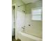 Bright bathroom featuring white tiled walls, bathtub and shower combo, and a window for natural light at 820 Maley St, Daytona Beach, FL 32114