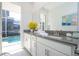 Bright bathroom featuring double vanity, gray countertop, and view of screened-in pool at 8964 Takeaway Way, Davenport, FL 33896