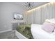 A modern bedroom is decorated in neutral colors and features a large television and light-filtering curtains at 8964 Takeaway Way, Davenport, FL 33896