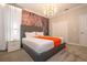 Bright bedroom with a gray bed frame, white bedding, statement wallpaper, and a modern chandelier at 8964 Takeaway Way, Davenport, FL 33896
