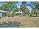 A spacious backyard featuring lush trees, grass, and partial view of a sunroom at 1115 Lake Francis Dr, Apopka, FL 32712
