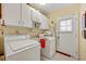 Bright laundry room with white appliances, overhead cabinets, and a door to the outside at 1115 Lake Francis Dr, Apopka, FL 32712
