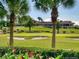 Picturesque view of the golf course with palm trees and flowering plants in the foreground at 116 Oakmont Ln, New Smyrna Beach, FL 32168