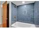Stylish tub/shower includes blue subway tile surround, glass shelving, and modern bronze shower fixtures at 127 Oak Ln, Ormond Beach, FL 32174