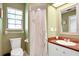 Cozy bathroom featuring a toilet, shower with curtain, unique mirror, and wood countertop with an oval sink at 127 Oak Ln, Ormond Beach, FL 32174