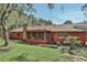 Charming red home featuring a screened-in porch and brick chimney, surrounded by lush greenery at 127 Oak Ln, Ormond Beach, FL 32174