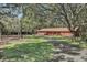 Secluded red home with a private drive surrounded by mature trees and a lush lawn at 127 Oak Ln, Ormond Beach, FL 32174