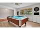 Bright game room featuring a billiard table, wood floors, and a window overlooking the landscaped yard at 127 Oak Ln, Ormond Beach, FL 32174