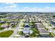 Expansive aerial view of a neighborhood with well-maintained homes and green spaces under a bright, partly cloudy sky at 13194 Magnolia Valley Dr, Clermont, FL 34711