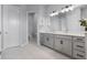Bright bathroom features a double sink vanity, white countertops, grey cabinets, and a separate toilet room at 13194 Magnolia Valley Dr, Clermont, FL 34711