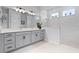 A bright bathroom features a double sink vanity, white countertops, grey cabinets, and a glass-enclosed shower at 13194 Magnolia Valley Dr, Clermont, FL 34711