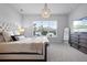 A luxurious bedroom features neutral walls, soft carpet, decorative chandelier, and a view of the landscape outside at 13194 Magnolia Valley Dr, Clermont, FL 34711