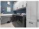 Well organized laundry room featuring modern washer and dryer, white cabinets, counter space, and stylish blue walls at 13194 Magnolia Valley Dr, Clermont, FL 34711