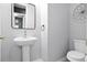 Stylish powder room featuring a pedestal sink, a modern mirror, neutral paint and a decorative floral wall hanging at 13194 Magnolia Valley Dr, Clermont, FL 34711