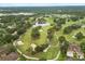 Aerial view showcasing a community golf course, featuring lush green fairways, mature trees, sand traps, and ponds at 14 Camino Real Blvd # 14, Howey In The Hills, FL 34737