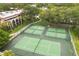 Aerial view of the community pickleball courts, located next to a residential building, surrounded by beautiful landscaping and greenery at 14 Camino Real Blvd # 14, Howey In The Hills, FL 34737