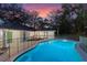 Backyard pool with security fence, lush trees, and exterior view of the charming white home at 140 Sweet Bay Cir, Lake Mary, FL 32746
