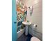 Compact bathroom featuring colorful tropical shower curtain, pedestal sink, and blue accent door at 1405 Periwinkle Ave, Deland, FL 32724