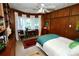 Comfortable bedroom with wood paneling, a ceiling fan, bay window, and built-in bookcase at 1405 Periwinkle Ave, Deland, FL 32724