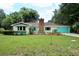 Inviting single-story home with a well-maintained lawn, turquoise accents and brick chimney at 1405 Periwinkle Ave, Deland, FL 32724